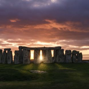 Stonehenge all'alba, con il sole che sorge dietro le pietre millenarie.